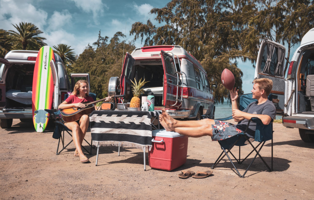 Friends throwing the ball next to their campervans in Hawaii